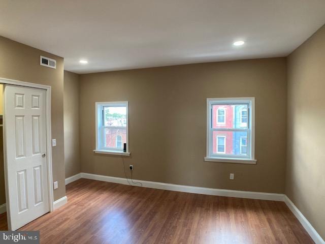 empty room with recessed lighting, wood finished floors, visible vents, and baseboards