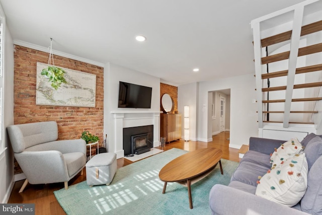 living area featuring stairs, brick wall, wood finished floors, and baseboards