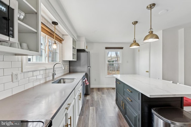 kitchen with light wood finished floors, stainless steel dishwasher, decorative backsplash, white cabinetry, and a sink