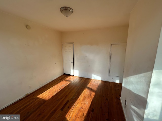 empty room with dark wood-type flooring and baseboards