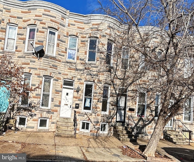 townhome / multi-family property featuring entry steps, stone siding, and central AC