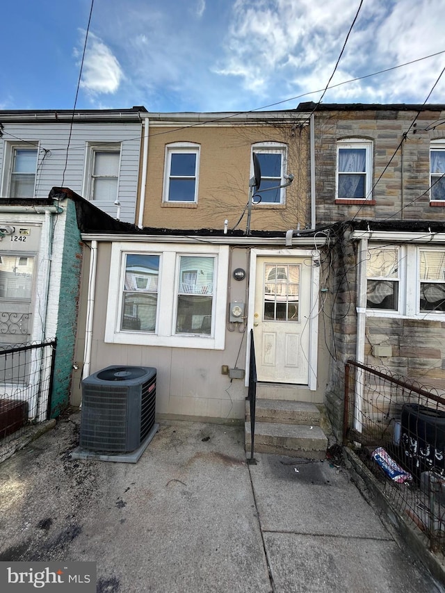 view of front of property with entry steps, fence, cooling unit, and a patio