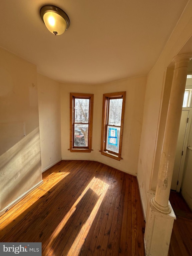 empty room with wood-type flooring and ornate columns