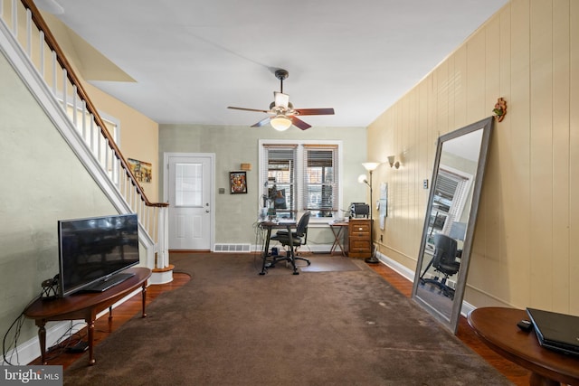 office space with visible vents, dark carpet, baseboards, and ceiling fan