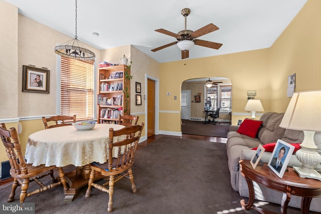 dining space with arched walkways, a ceiling fan, and baseboards