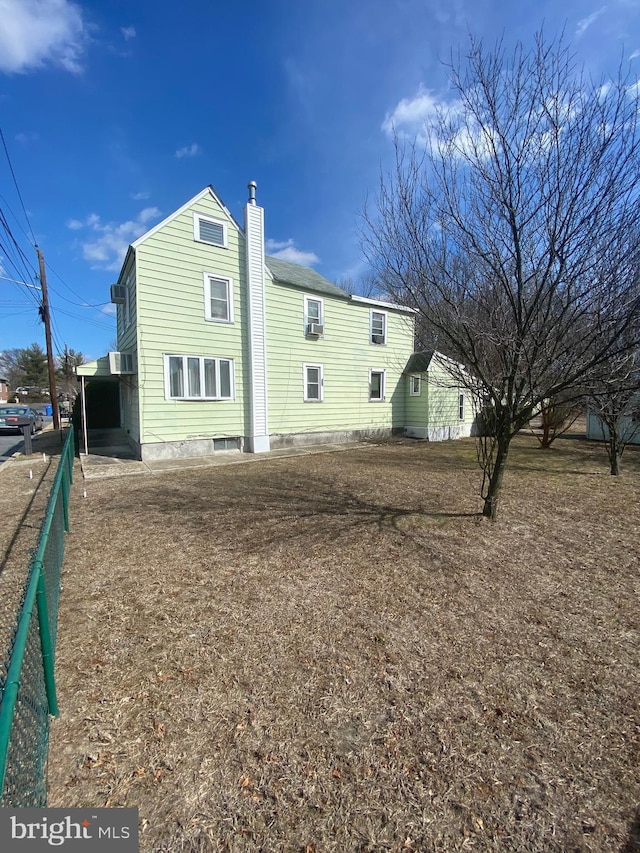 rear view of property featuring a chimney and fence