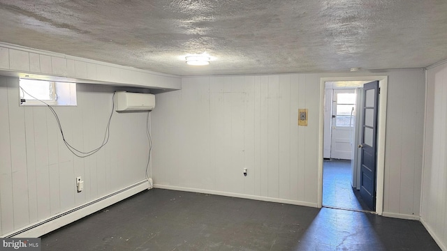 basement with a baseboard radiator, a wall mounted air conditioner, a textured ceiling, and baseboards