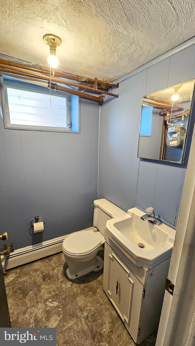 half bath featuring toilet, a baseboard radiator, a textured ceiling, and vanity