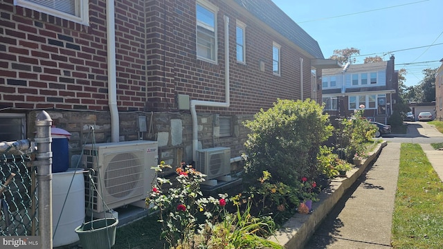 view of property exterior with ac unit, fence, and brick siding