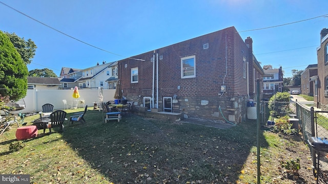 rear view of house with a yard, a residential view, brick siding, and fence