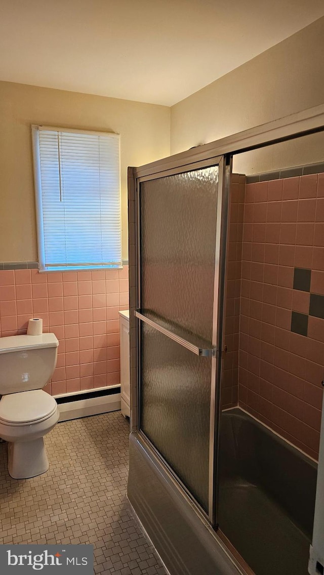 bathroom featuring shower / bath combination with glass door, tile walls, baseboard heating, and tile patterned floors