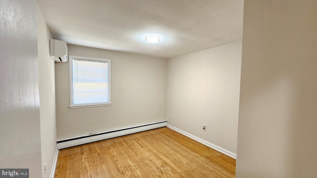 unfurnished room featuring a baseboard heating unit, light wood finished floors, a wall mounted AC, and baseboards