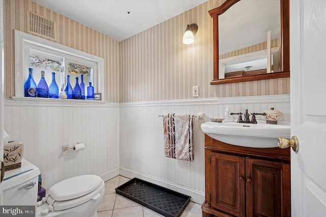 bathroom with a wainscoted wall, visible vents, toilet, wallpapered walls, and tile patterned flooring