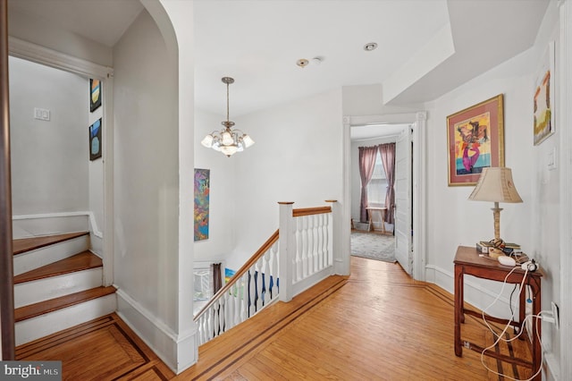 interior space featuring baseboards, an upstairs landing, arched walkways, and wood finished floors