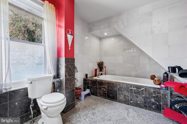 bathroom with toilet, tile walls, and a garden tub