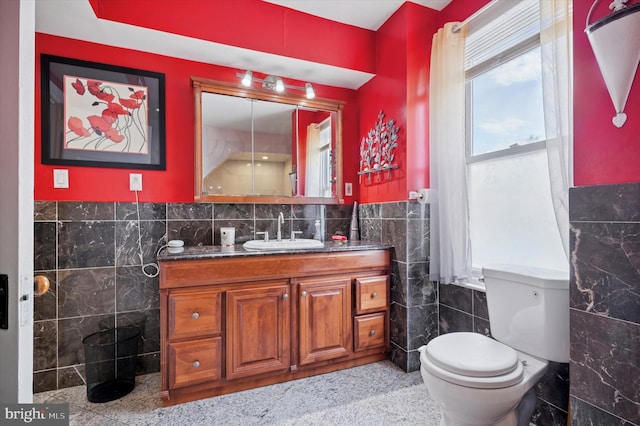 bathroom featuring a wainscoted wall, toilet, tile walls, and vanity