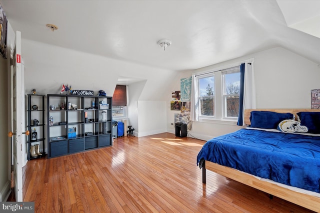 bedroom with vaulted ceiling, baseboards, and wood-type flooring