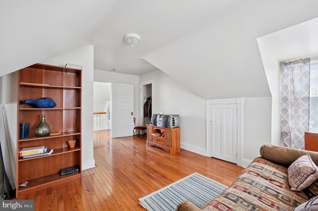 living room featuring light wood-type flooring, lofted ceiling, and baseboards