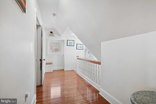 corridor featuring baseboards, lofted ceiling, and wood-type flooring