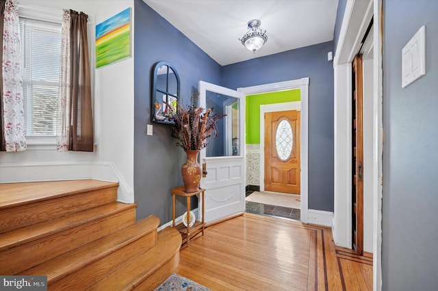 entryway featuring baseboards, wood finished floors, and stairs