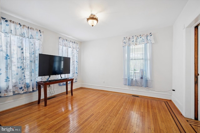 living area with visible vents, baseboards, and hardwood / wood-style floors