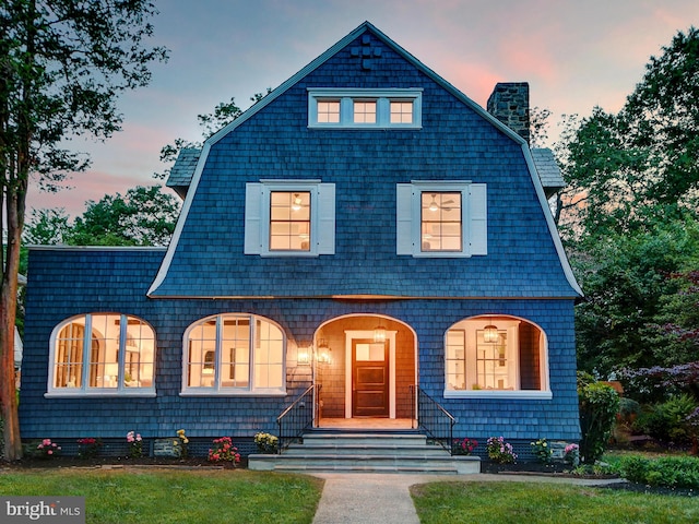 shingle-style home with a chimney and a gambrel roof