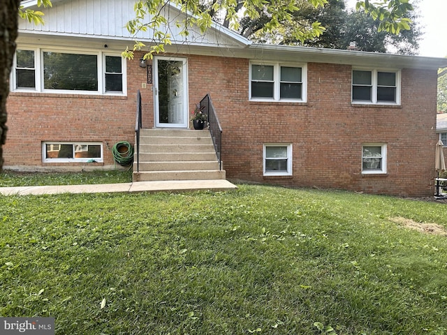 view of front of house with entry steps, brick siding, and a front yard