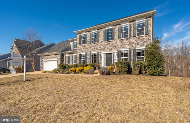 colonial home featuring a garage, stone siding, a front lawn, and concrete driveway