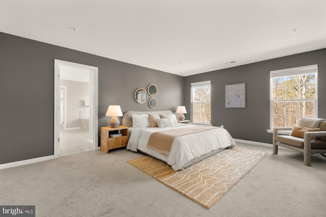 carpeted bedroom featuring ensuite bath and baseboards