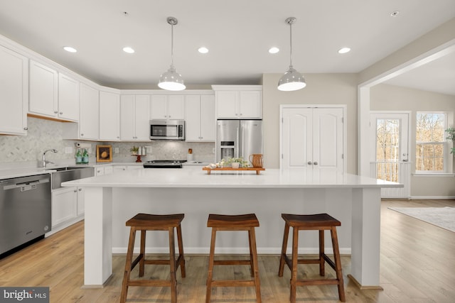 kitchen with light countertops, decorative backsplash, appliances with stainless steel finishes, white cabinets, and a sink