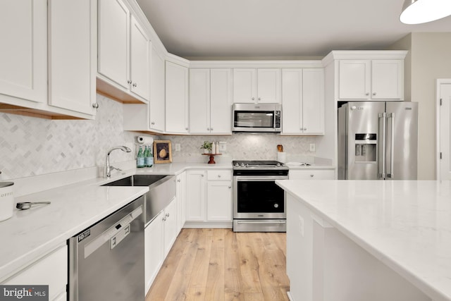 kitchen with appliances with stainless steel finishes, white cabinetry, and backsplash