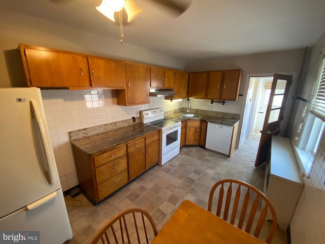 kitchen featuring dark countertops, white appliances, brown cabinets, and a sink