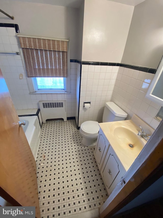 full bath featuring tile walls, toilet, radiator heating unit, vanity, and a tub