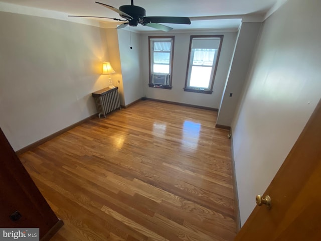 unfurnished room featuring light wood-style floors, radiator, baseboards, and a ceiling fan