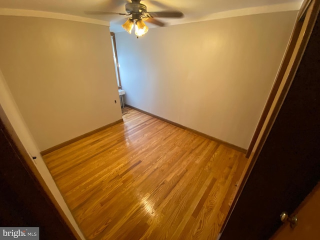 empty room featuring light wood-type flooring, a ceiling fan, and baseboards