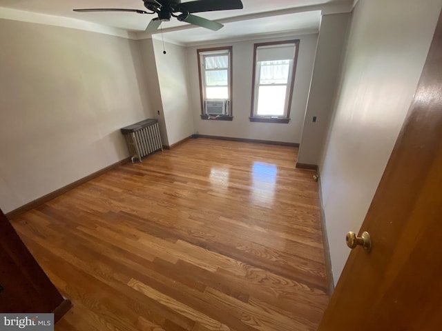 spare room featuring radiator, light wood-type flooring, and baseboards