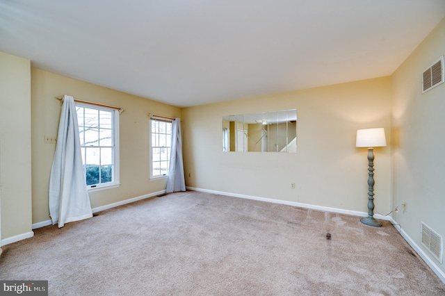 spare room featuring carpet, visible vents, and baseboards