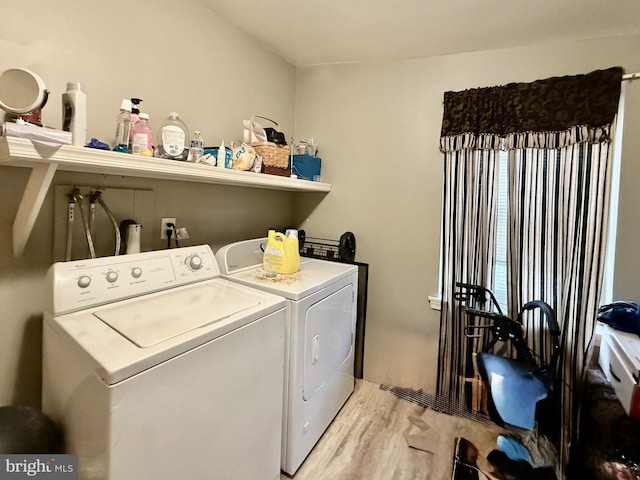 clothes washing area with laundry area, separate washer and dryer, and light wood-type flooring