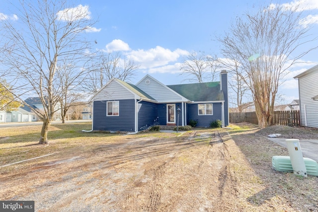 bungalow with driveway, a chimney, and fence