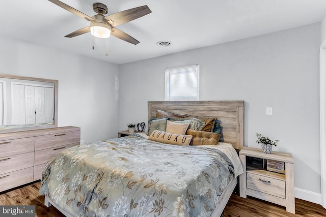 bedroom featuring a ceiling fan, dark wood-style flooring, visible vents, and baseboards