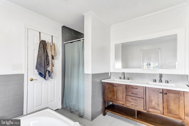 full bath featuring double vanity, crown molding, tile walls, and a sink