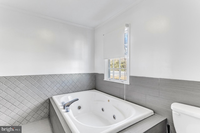 full bath featuring crown molding, tile walls, toilet, wainscoting, and a jetted tub