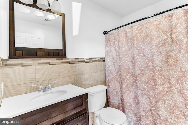 bathroom with visible vents, tile walls, toilet, and vanity