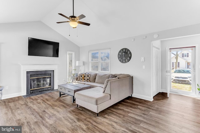 living room with a fireplace with flush hearth, baseboards, vaulted ceiling, and wood finished floors