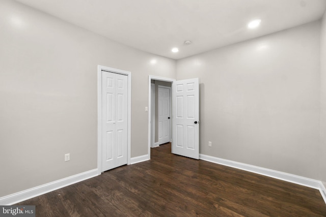 unfurnished bedroom featuring baseboards, dark wood finished floors, a closet, and recessed lighting