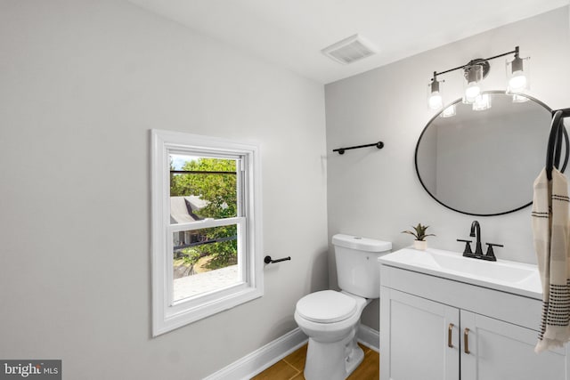 bathroom featuring toilet, vanity, visible vents, and baseboards