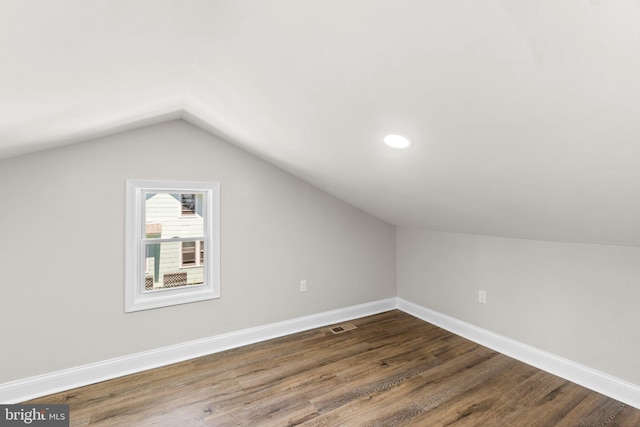 additional living space with lofted ceiling, baseboards, visible vents, and dark wood finished floors