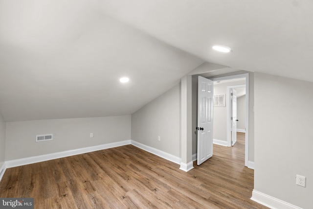 bonus room with visible vents, baseboards, vaulted ceiling, and wood finished floors