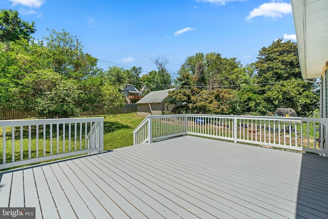 wooden terrace featuring an outbuilding, a yard, and fence