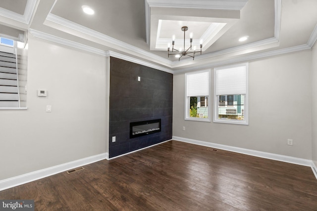 unfurnished living room featuring a large fireplace, ornamental molding, dark wood finished floors, and an inviting chandelier